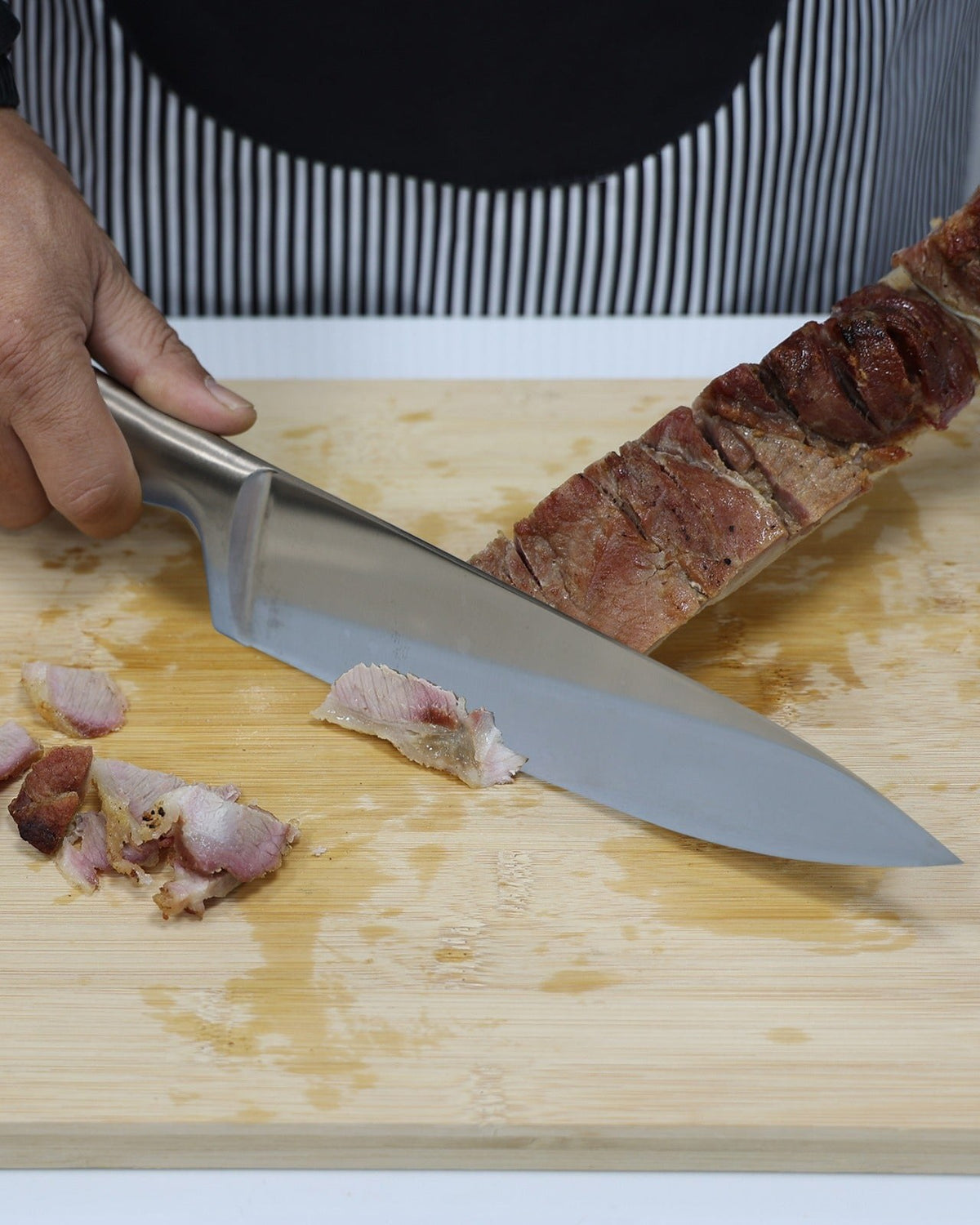 Faca Zurique de aço inox fatiando carne assada sobre tábua de bambu