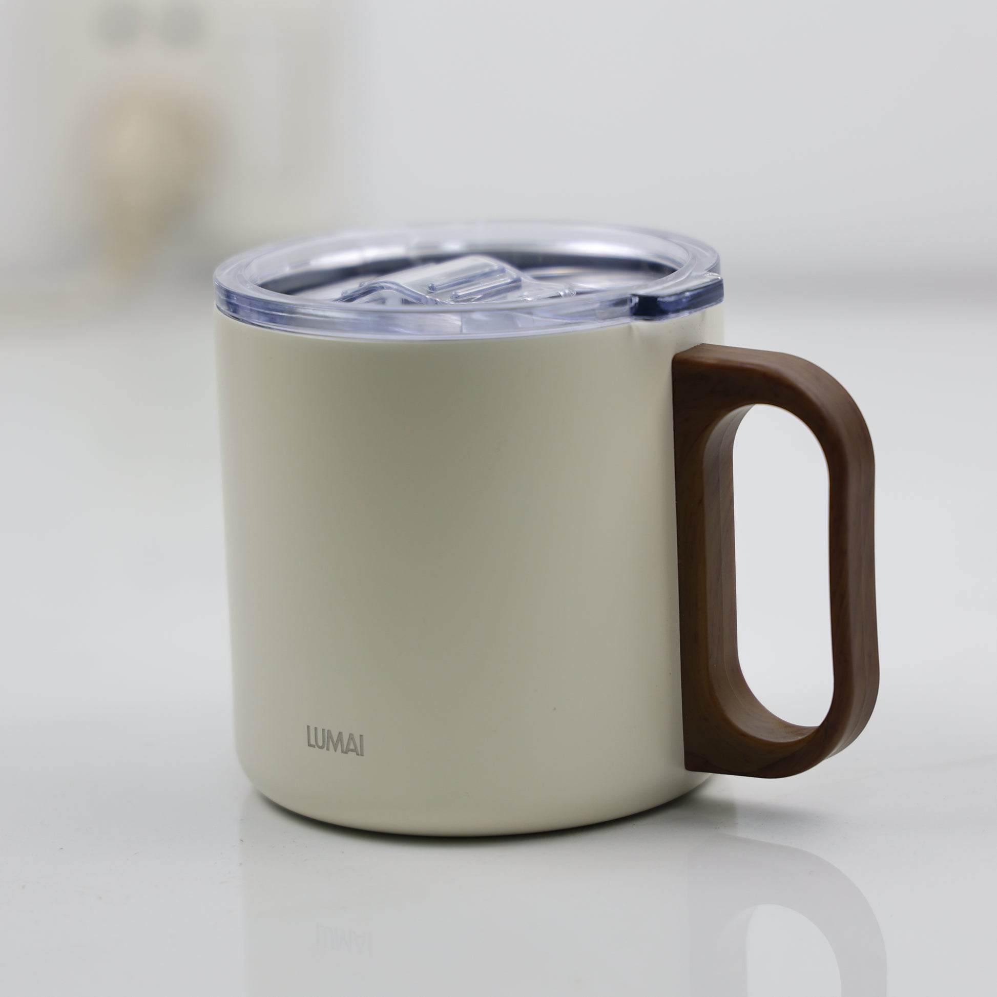 Detalhe da base da caneca em cor off-white com tampa translúcida fechada e alça tipo madeira escura