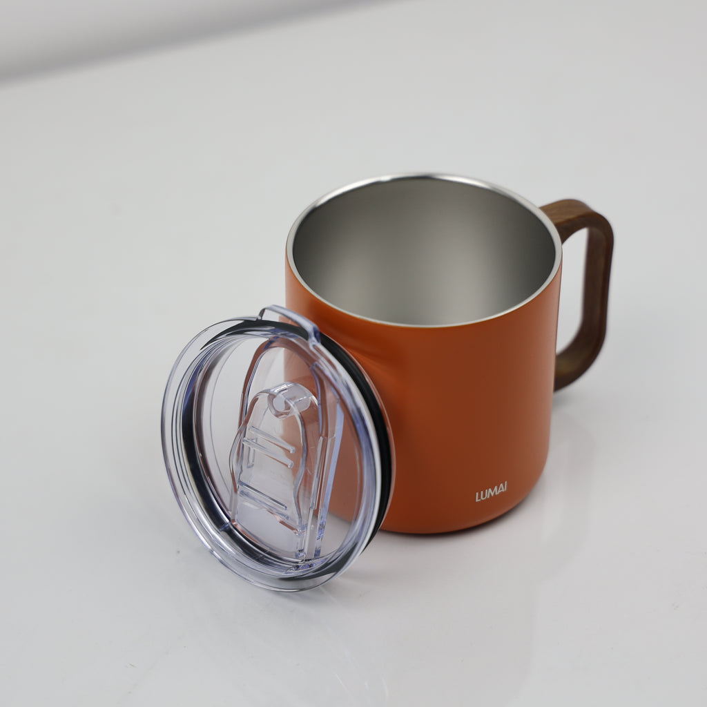 Caneca térmica laranja aberta com tampa transparente ao lado, mostrando interior em aço inox