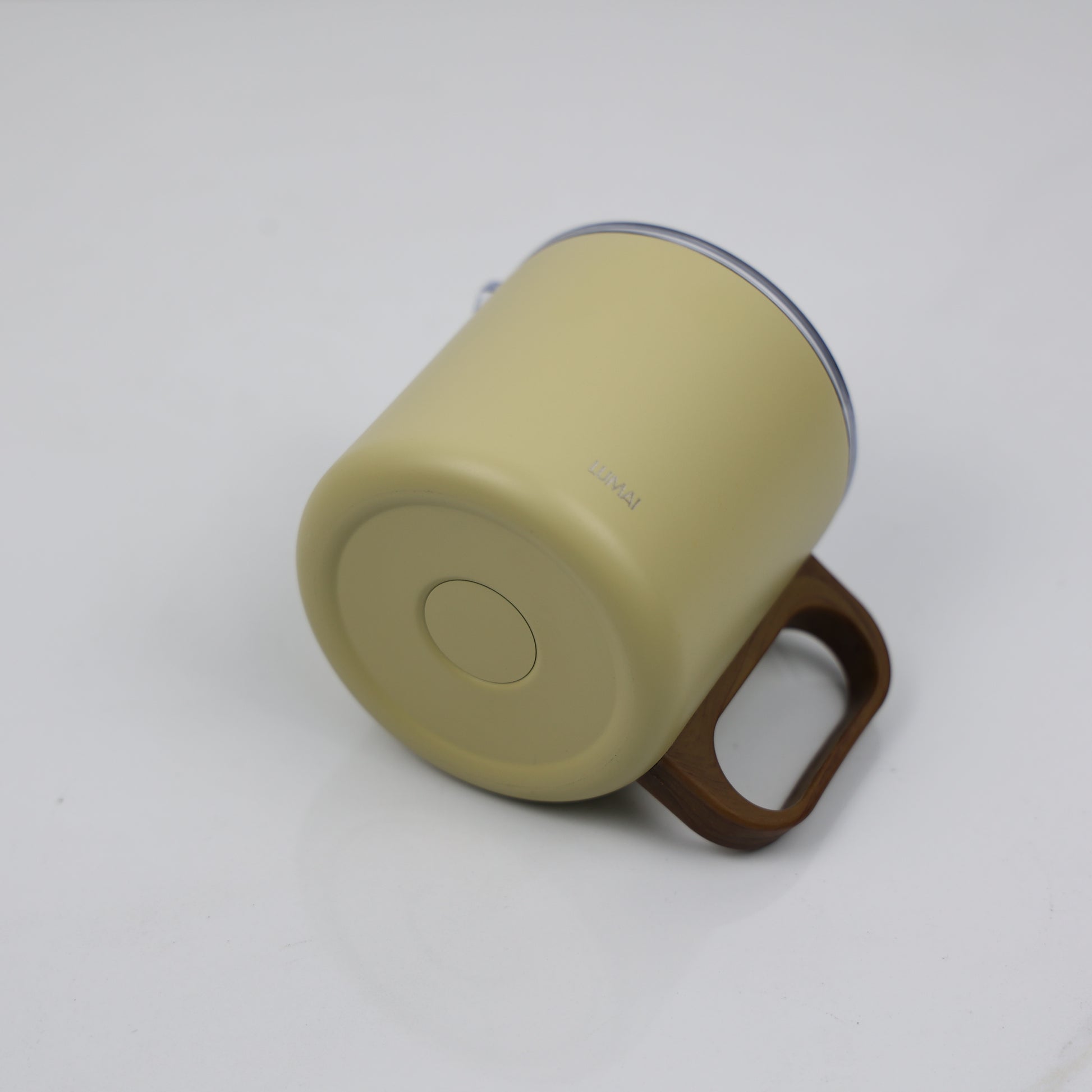 Ângulo inferior mostrando base amarela fosca da caneca térmica com logo LUMAI gravado e alça amadeirada