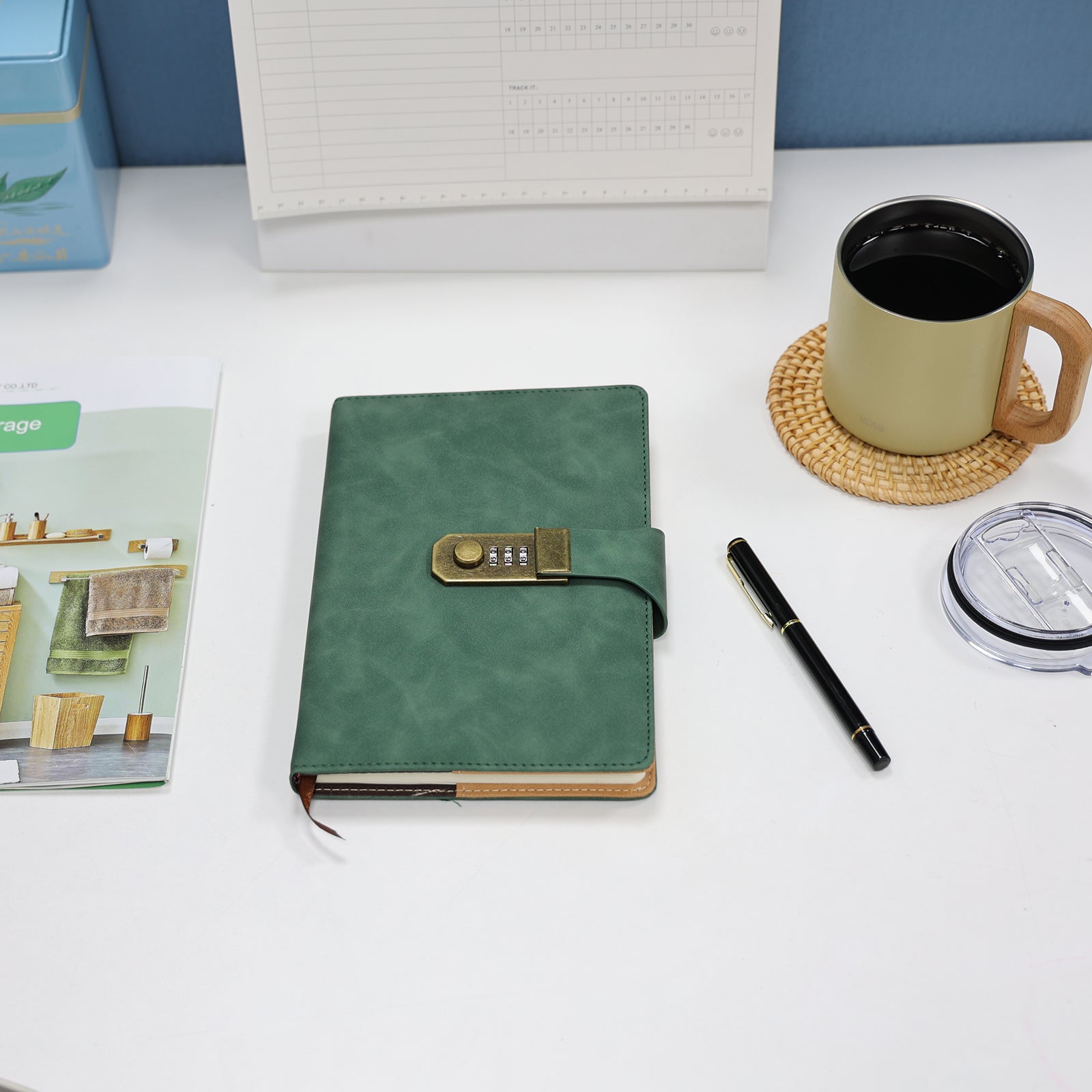 Foto lifestyle do Caderno com Cadeado Cartagena LUMAI verde sobre mesa com caneta, caneca e revistas, em ambiente de estudo e organização.