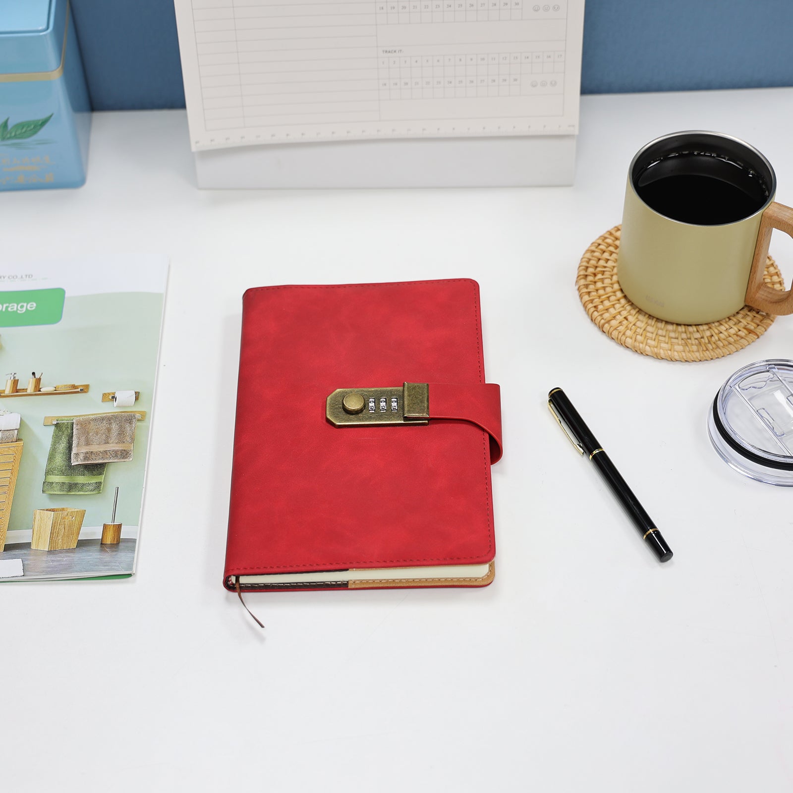 Foto lifestyle do Caderno com Cadeado Cartagena LUMAI vermelho sobre mesa com caneta, caneca e revistas, mostrando o caderno em ambiente de estudo.