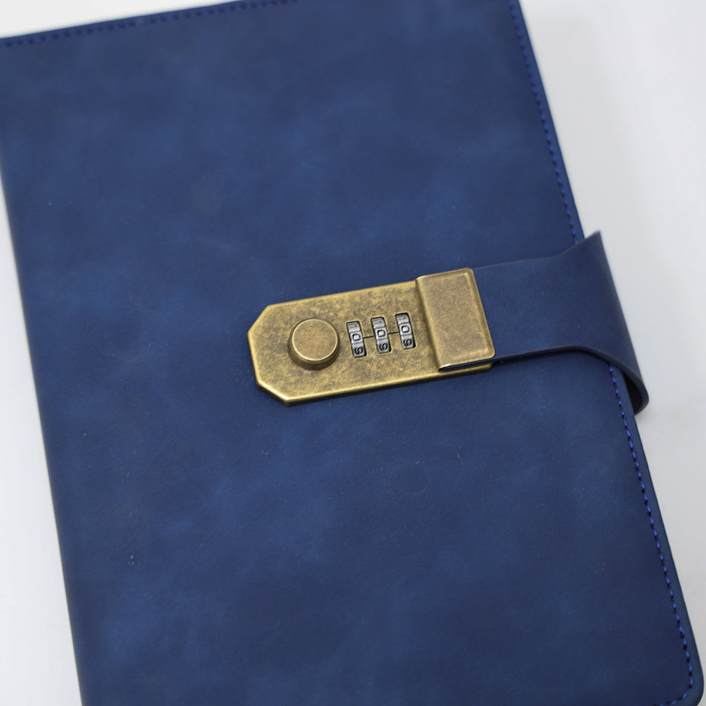 Close-up do cadeado de combinação dourado do caderno diário de couro azul marinho, mostrando o mecanismo de fechamento seguro e acabamento premium do produto.