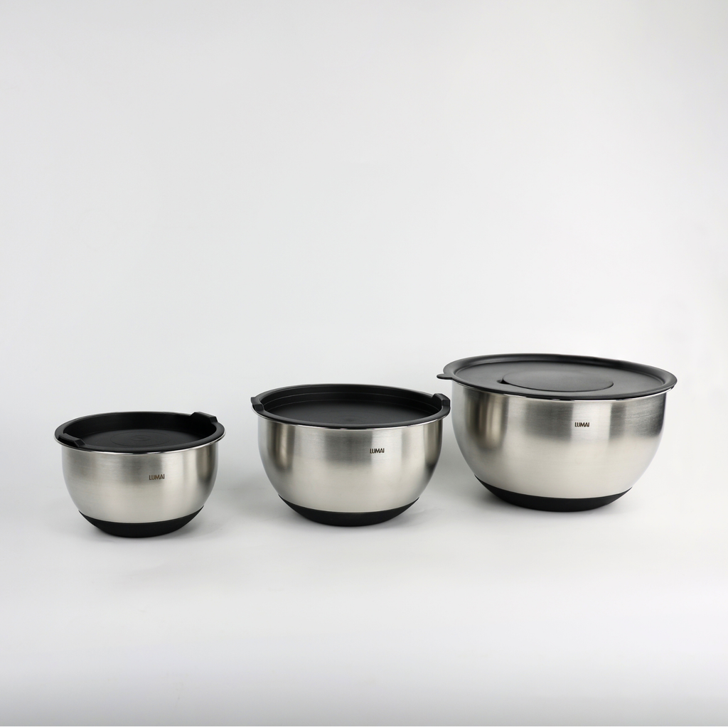 Foto de produto do Kit de Tigelas de Inox LUMAI com 3 tamanhos diferentes e tampas pretas, exibidos sobre fundo branco, ideais para uso na cozinha.