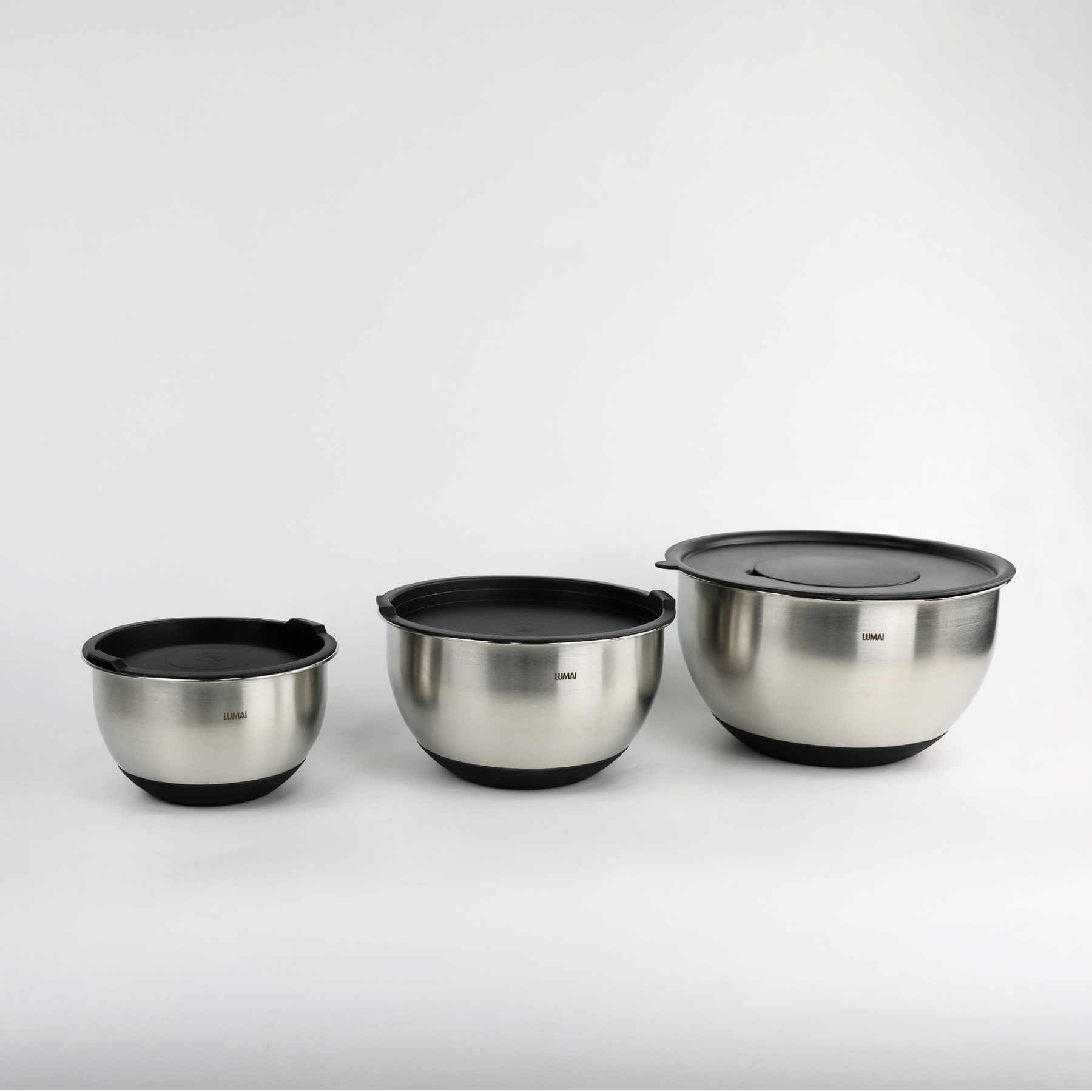 Foto de produto do Kit de Tigelas de Inox LUMAI com 3 tamanhos diferentes e tampas pretas, exibidos sobre fundo branco, ideais para uso na cozinha.