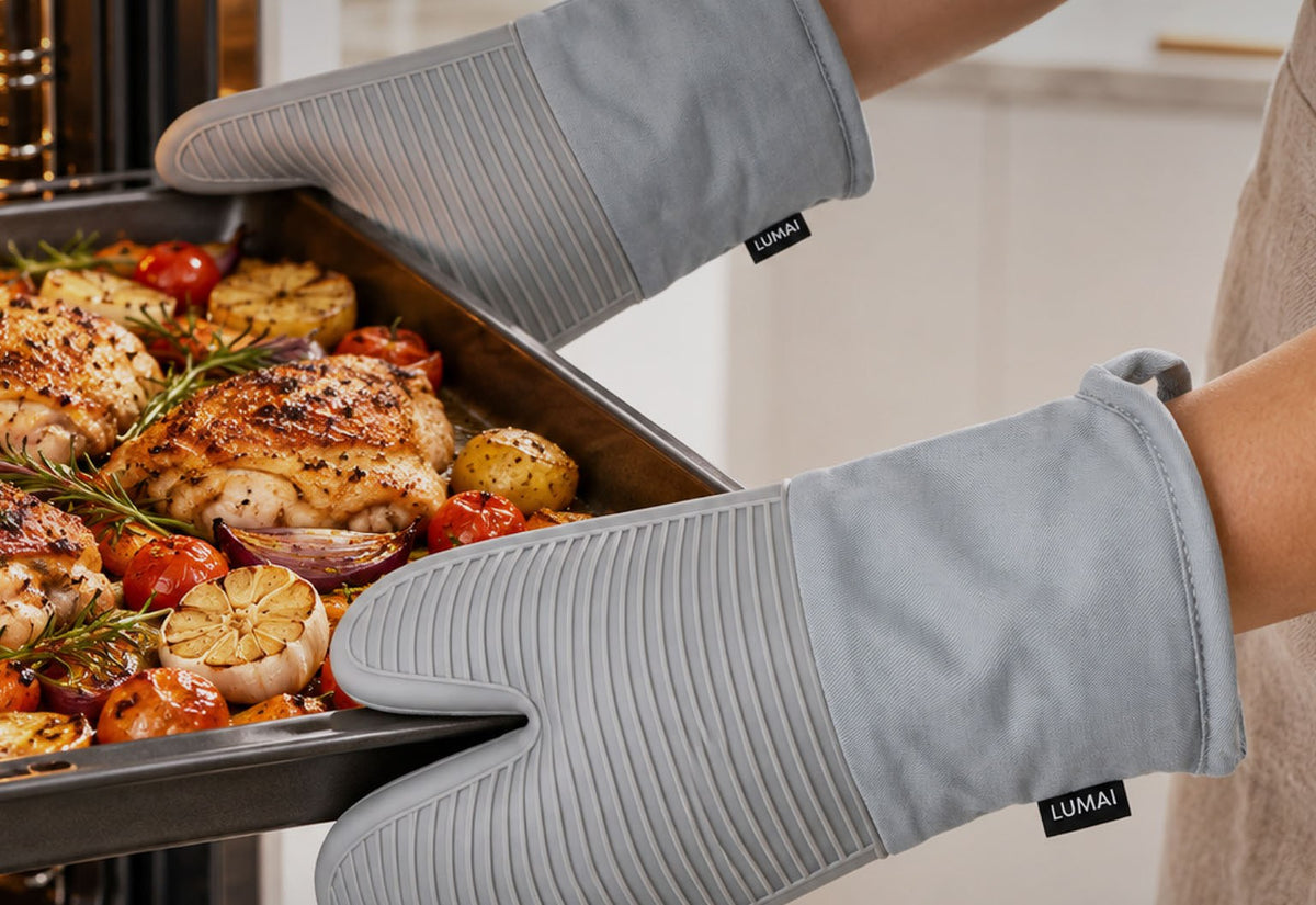 Luvas de cozinha Nápoles cinza segurando uma assadeira com frango e legumes na saída do forno